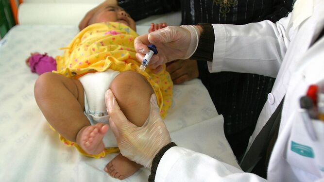 Un profesional de enfermería vacuna  a una bebé .
