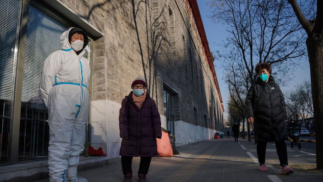 Un sanitario voluntario ayuda a una señora en Pekín.