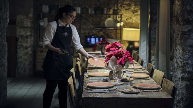 Una camarera prepara una mesa para una comida navideña en el restaurante La Chancha.