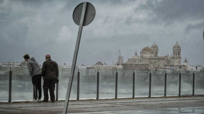 Dos personas observan el fuerte oleaje en Cádiz