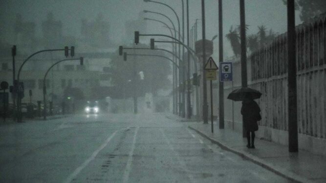 Una persona camina por Cádiz en mitad de un aguacero en la mañana del domingo