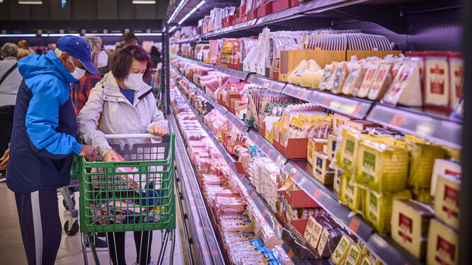 Consumidor comprando en el área de refrigerados de un supermercado.