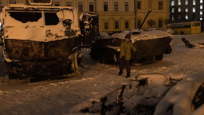 Un niño juega con la nieve junto a unos vehículos militares rusos destruidos en Kiev.