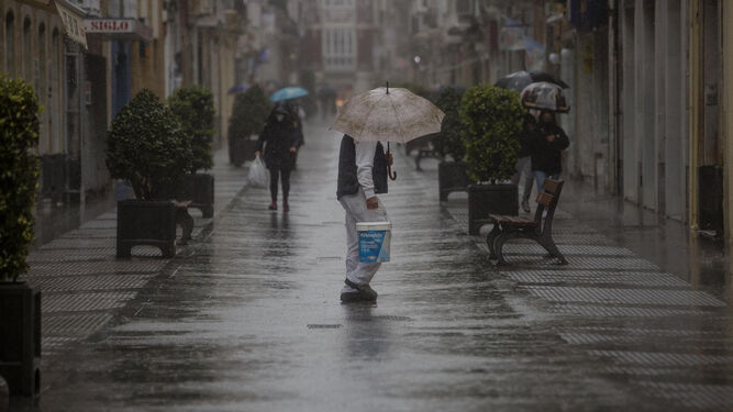 Un hombre camina por calle Ancha de Cádiz, en medio de una tromba de agua