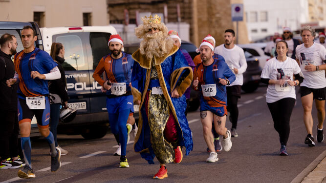 Un rey mago ataviado de atleta encabeza un grupo de corredores con detalles navideños.