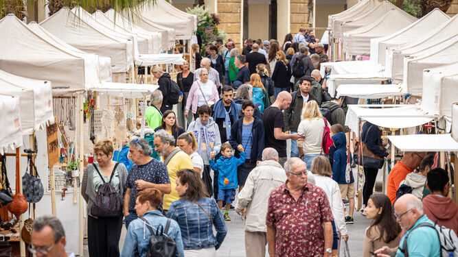 Turistas pasean por una plaza de San Juan de Dios de Cádiz llena de puestos artesanales
