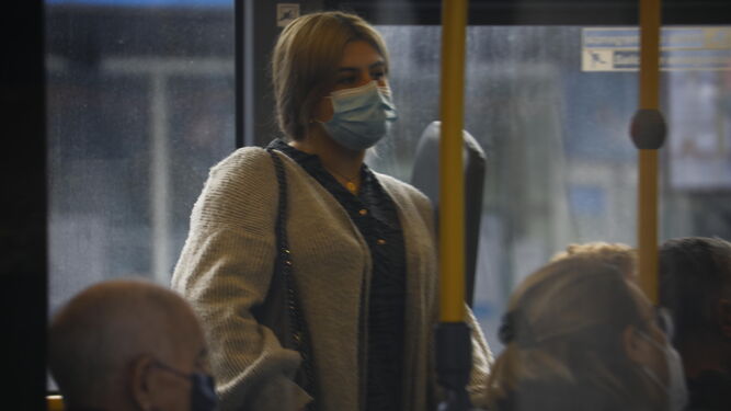 Una mujer, protegida por su mascarilla, en el interior de un autobús.