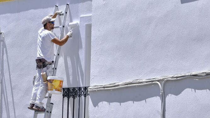Un pintor enluce una de las blancas fachadas de una vivienda de El Bosque