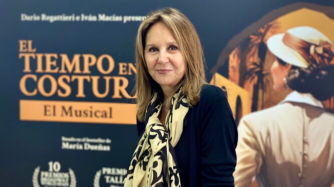 La escritora María Dueñas, con el cartel de 'El tiempo entre costuras. El Musical'.