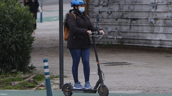 Una mujer circula con su patinete eléctrico por el carril bici.