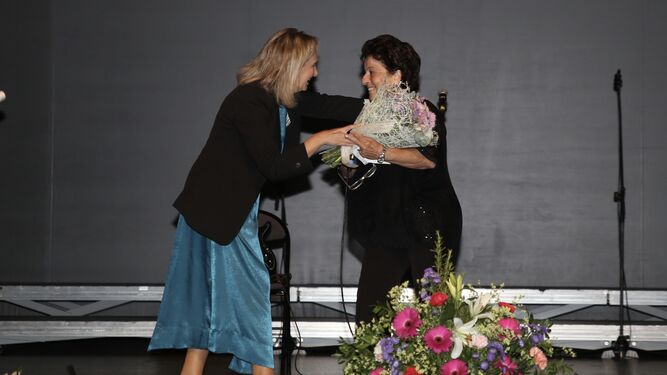 Lola Campos, haciendo entrega de un ramo de flores a Coca García Junquero, alma mater del encuentro.