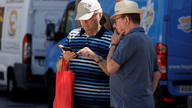 Dos turistas consultan el móvil.
