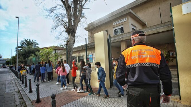 Alumnos del colegio Tierno Galván salen del centro educativo ante un voluntario de Protección Civil en una imagen de archivo.