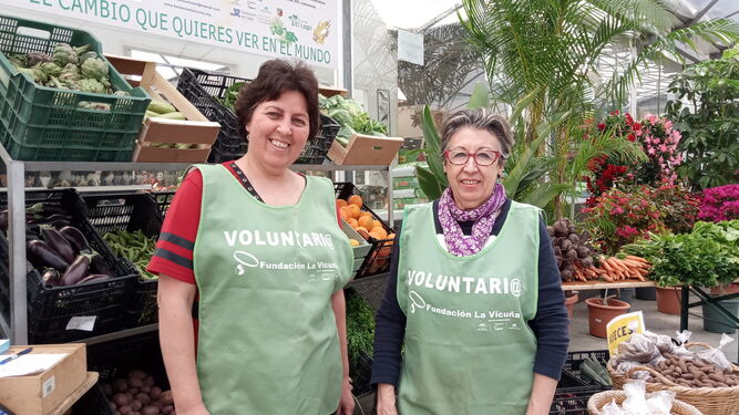 Dos voluntarias de la Fundación La Vicuña, en uno de los mercados con productos del Huerto Solidario.