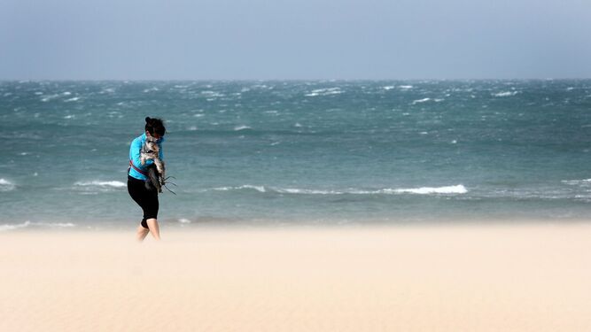 Una mujer pasea por la playa de Cádiz en pleno temporal de levante