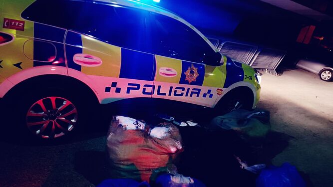 Un vehículo policial junto a los bultos con las prendas decomisadas.