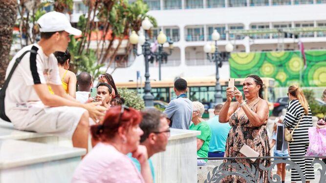 Turistas haciendo fotos en la plaza de San Juan de Dios con un crucero de fondo
