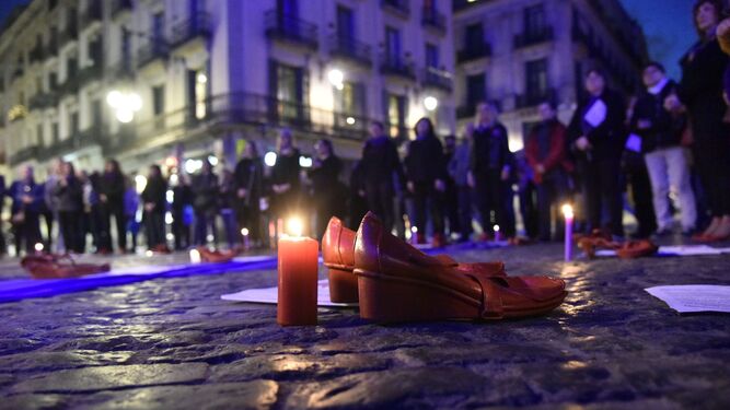 Zapatos rojos y una vela durante una concentración contra la violencia machista.
