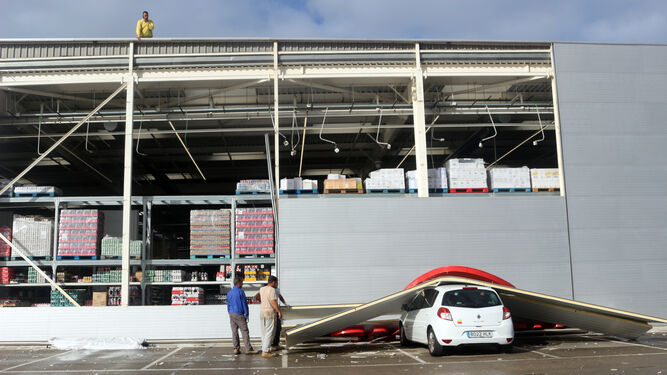 Trabajadores retiran las planchas que cayeron al parking del supermercado
