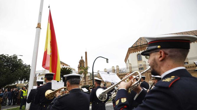 La banda del Tercio de la Armada interpreta el himno de España mientras se iza la bandera en la plaza de Sevilla.