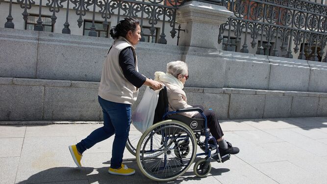 Una mujer en silla de ruedas, con su cuidadora.