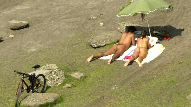 Una pareja toma el sol desnudos.