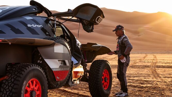 Carlos Sainz observa a su Audi en el desierto.