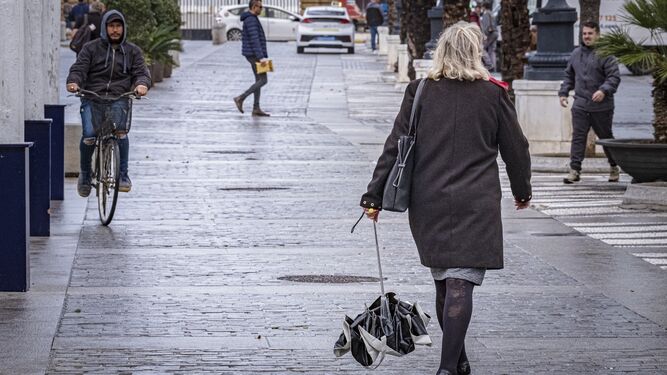 Una mujer, con su paraguas cerrado, por Cádiz.