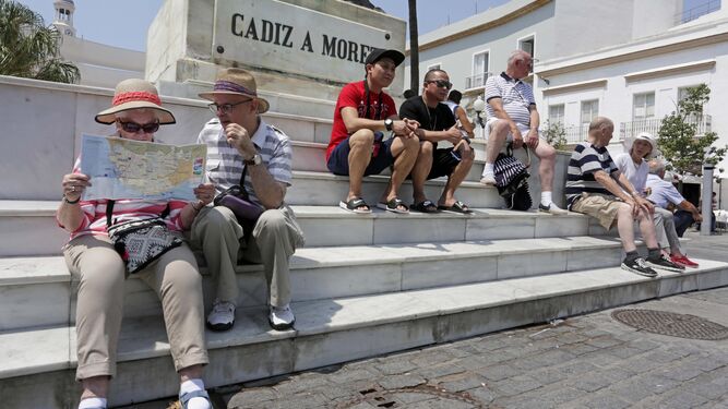Un grupo de turistas reposa en la escalerilla del monumento a Moret, en la plaza de San Juan de Dios, antes de seguir conociendo la ciudad.