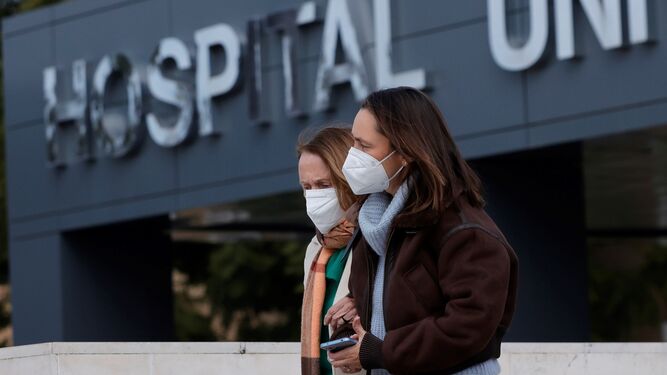 Dos jóvenes con mascarillas salen de un hospital.