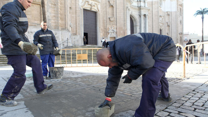 Trabajadores de los programas de Empleo de la Junta entre 2017 y 2019 arreglan el suelo de la Plaza de la Catedral de Cádiz.