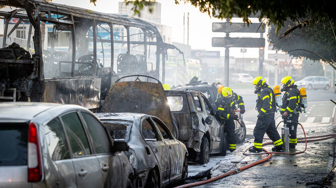 El autobús calcinado y varios de los coches afectados también por el fuego.