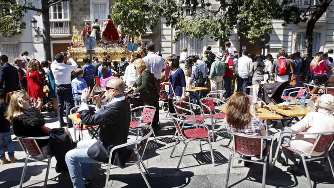 Turistas en una terraza en Cádiz y un paso de Semana Santa al fondo.