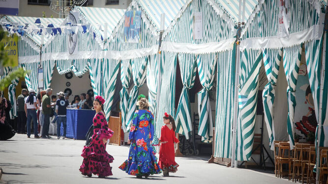 Dos mujeres y una niña pasean por el recinto de la Feria del Moscatel en Chipiona en la edición del 2024.